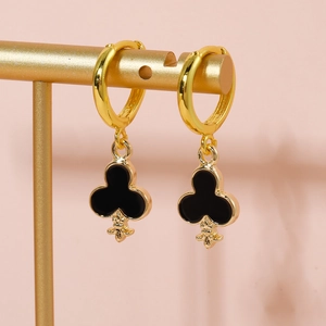 Detailed macro shot of gold-plated club pendant earrings with black enamel on a display stand