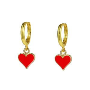 Macro detail of golden hoop earring with vibrant red enamel heart pendant on white background