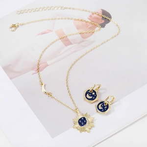 Celestial gold necklace and earring set with star and moon charms in blue enamel