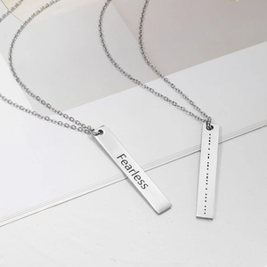 Detailed macro shot of silver stainless steel bar pendants with Fearless engraving and Morse code