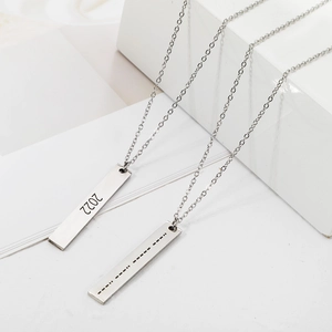 Macro shot of silver stainless steel bar necklaces with 2022 and Morse code engraving
