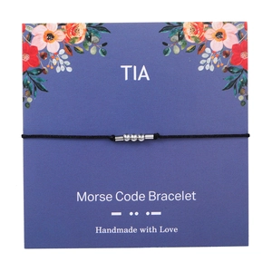 Detailed view of handmade Morse code bracelet with silver beads on a floral display card
