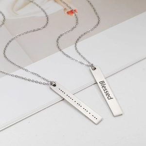 Detail view of silver Morse code necklace engraved with Blessed on stainless steel