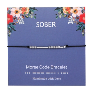 Detail of SOBER Morse Code Bracelet with silver beads on a floral gift card display