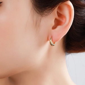 Polished gold round hoop earrings shown on ear for a minimalist jewelry look
