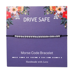 Detail of Morse code bracelet with silver beads on floral card packaging