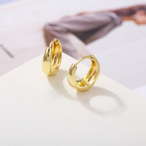 Detailed view of polished gold plated hoop earrings on a white minimalist pedestal stand