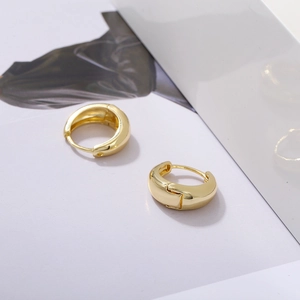 Macro shot of thick gold-plated hoop earrings with polished mirror finish and hinge closure