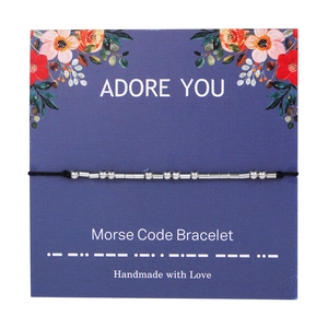 Morse Code Bracelet with silver beads on adjustable black cord on a floral display card