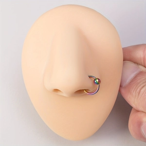 Rainbow stainless steel captive bead ring set shown on a silicone nose model display