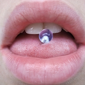 Piercing de langue en acrylique violet clair porté sur le bout de la langue