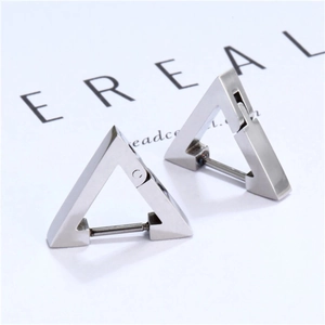 Macro detail of minimalist silver triangle hoop earrings on a fashion magazine background