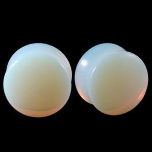Macro view of blue opal glass ear plugs with polished dual-flare design for stretching