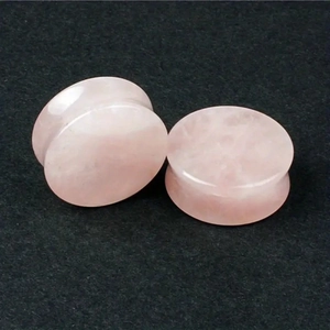 Detailed macro view of pink rose quartz ear plugs with natural stone texture and finish
