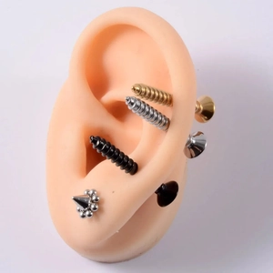 Detail showing various colors of screw and cone stud earrings on a silicone ear model