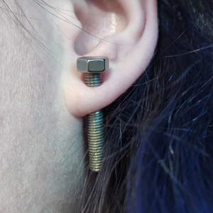 Punk style silver stainless steel screw shaped stud earrings worn on ear lobe