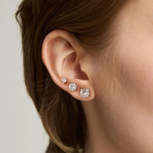 Vue détaillée de trois boucles d'oreilles en zircone ronde à quatre griffes de tailles dégradées