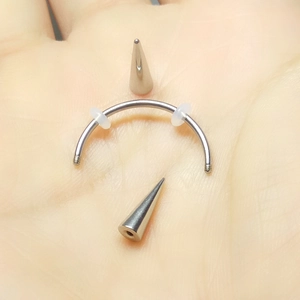 Detail of medical steel vampire teeth piercing with curved bar and silver cone spikes