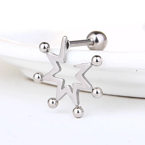 Vue macro d'une boucle d'oreille étoile en acier argenté avec boules sur un plat en céramique