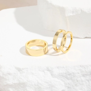 Minimalistisches 3er-Set 18K vergoldete Edelstahlringe auf einem weißen Steinsockel