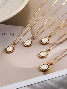 Détail des pendentifs lettres dorées avec émail blanc sur une chaîne minimaliste