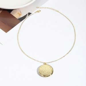 Λεπτομερής κοντινή λήψη χρυσού μενταγιόν locket με περίπλοκο ανάγλυφο σχέδιο λουλουδιών