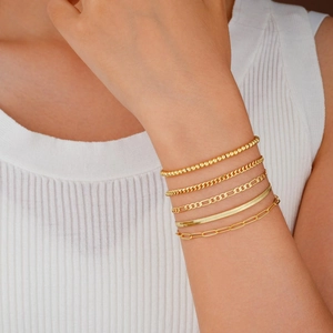 Nahaufnahme von fünf goldenen Armbändern mit Figaro- und Schlangenketten am Handgelenk