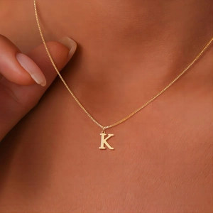 Close-up of polished gold letter K pendant necklace on model showing elegant detail