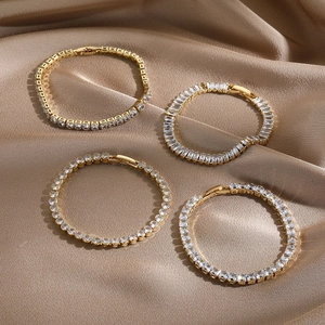 Detail of four 14k gold-plated tennis bracelets with various zircon cuts on silk background