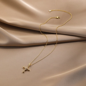 Detail of gold cross pendant necklace with zircon inlay on brown silk background
