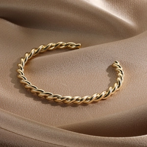 Detailed view of twisted rope design 14k gold plated cuff bracelet on silk background