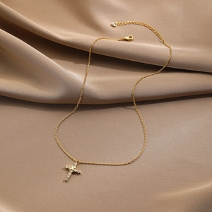 Macro detail of gold-plated cross necklace with zircon stones on brown silk fabric