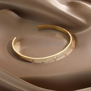 Detailed close-up of a 14k gold plated cuff bracelet with fine brushed texture and zircons