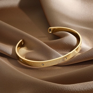Detail of 14k gold plated bangle with brushed finish and star-set crystal accents