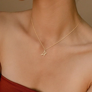 Dettaglio di una collana con ciondolo a lettera A dorata e cuore sulla clavicola