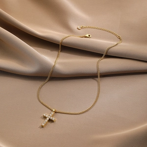 Detail of gold cross pendant necklace with white crystals on silk fabric background