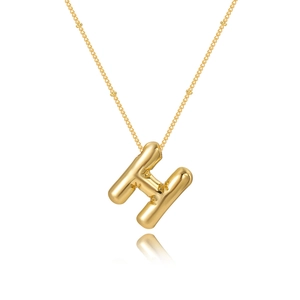 Macro detail of bubble letter H pendant with star patterns and beaded gold chain