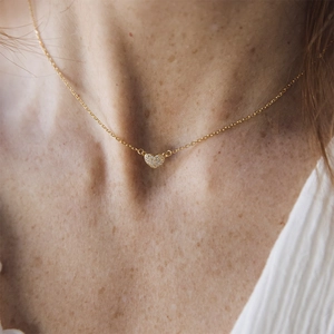 Close-up of minimalist gold heart pendant necklace with zircon pavé on model's neck