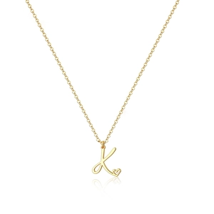 Dettaglio della collana dorata con ciondolo lettera K e piccolo cuore con riflesso a specchio