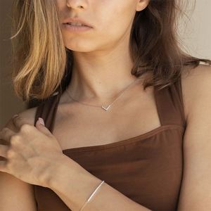 Close-up of elegant V-shaped zircon necklace and diamond bar bracelet on a model
