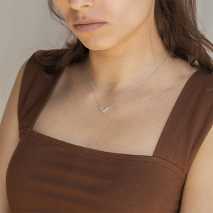 Close-up of a delicate silver V-shaped pendant necklace with cubic zirconia on model