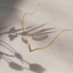 Detailed view of a gold V-shaped pendant necklace with sparkling micro-pave zircons