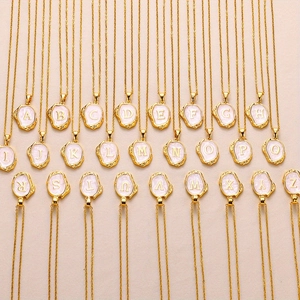 Set van 26 vintage gouden letterhangers met roze emaille op een getextureerde achtergrond
