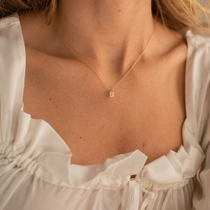 Détail d'un collier doré avec pendentif zircon rectangulaire sur un chemisier blanc