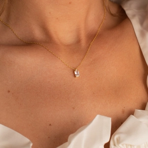 Gros plan d'un collier doré élégant avec un pendentif en zircon rectangulaire taillé
