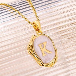 Vintage gouden letter K ketting met marmeren textuur en een getextureerd ovaal frame