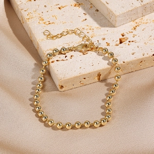 Close-up of golden beaded chain bracelet with high polish finish on stone background
