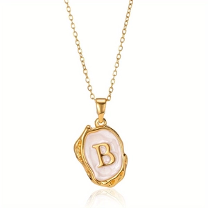 Macro-opname van gouden letter B hanger met gehamerde textuur en wit emaille