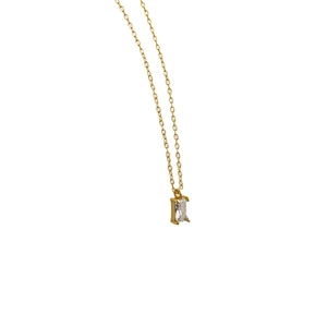 Detail view of gold chain necklace featuring a rectangular clear zircon pendant in four-prong setting