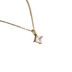 Detailed view of a gold princess cut zircon pendant necklace with small accent stones